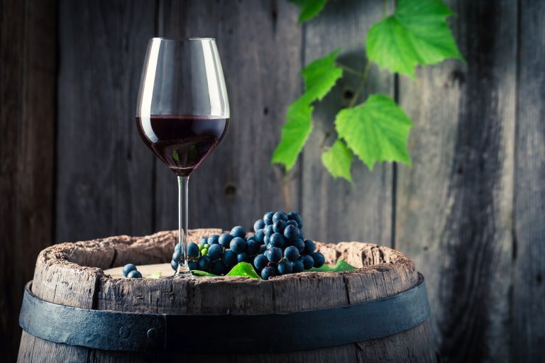 Pahar de vin roșu Cabernet Sauvignon pe butoi de lemn cu struguri