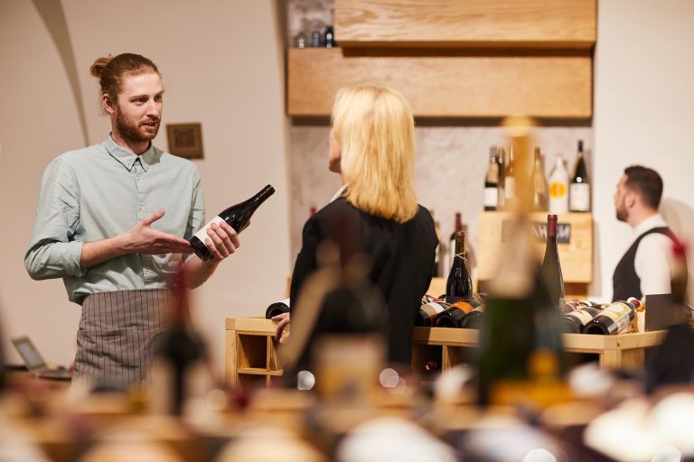 Consultant de vin prezent&acirc;nd o sticlă unui client