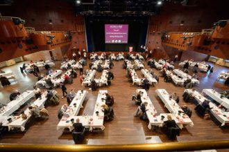 Sala de degustare a concursului internațional de vinuri Mundus Vini 2023, cu zeci de jurați evaluând probe de vin.