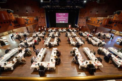 Sala de degustare a concursului internațional de vinuri Mundus Vini 2023, cu zeci de jurați evaluând probe de vin.