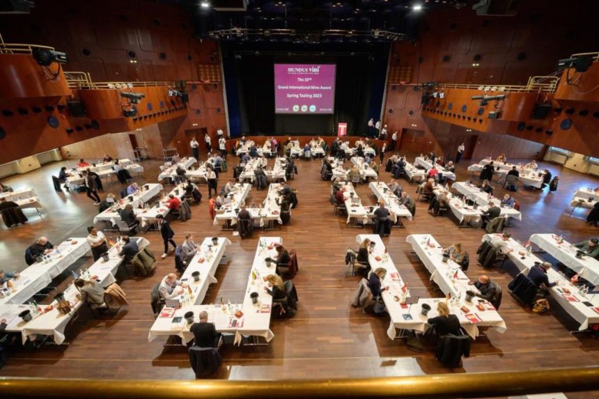Sala de degustare a concursului internațional de vinuri Mundus Vini 2023, cu zeci de jurați evaluând probe de vin.