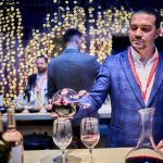 Vinuri românești de descoperit: Ce noutăți am gustat la RO-Wine 2025 Meta descriere Descoperă cele mai interesante vinuri românești prezentate la festivalul RO-Wine 2025 – ediția de toamnă. Jidvei, SERVE, Vintruvian, Gramofon și multe alte crame au adus vinuri de colecție și experiențe memorabile. RO-Wine 2025: un festival al descoperirilor de toamnă Tradiția festivalurilor de vin spune că primăvara îți prezinți vinurile albe, pentru vara care se apropie, iar toamna – vinurile roșii din recolta anului trecut. Doar că producătorii noștri au înțeles repede că festivalurile atrag un alt public, de la profesioniștii din horeca, interesați de vinuri speciale, la iubitorii de vin care își caută vinuri pentru colecții, pentru seri speciale alături de prieteni sau de savurat pe îndelete. Așa că tradiția vinurilor proaspete a început să se estompeze, iar oferta prezentată să aducă tot mai des, alături de noutăți, vinuri mai vechi, unele chiar nelansate, care mai au nevoie de ceva timp „ca să se așeze”. Așa că, pe scurt, vă spunem mai jos la ce noutăți vă puteți aștepta în perioada următoare. Vinuri excelente, care le fac cinste producătorilor și care ne pot reprezenta oriunde în lume sau care deja au fost medaliate la concursuri importante. Jidvei – colecția Spirit și vinuri românești premiate internațional Spirit – trei vinuri speciale Jidvei a adus în premieră gama Spirit, o colecție de trei vinuri speciale – Chardonnay 2023 (baricat 6 luni), Fetească regală 2023 (baricată tot șase luni, dar în butoaie aflate la a doua întrebuințare) și un cupaj rose de Pinot noir, Syrah și Cabernet Sauvignon. Dacă Chardonnay-ul este oarecum previzibil, în notele clasice deja cunoscute – bun, gustos, rotund, cu accentele de lemn perfect integrate, Feteasca regală este o surpriză foarte plăcută și extrem de elegantă. Alegerea unor butoaie care transferă vinului mai puține arome s-a dovedit inspirată – vinul a câștigat note delicate dar, în același timp, și-a amplificat propriile resurse aromatice, prin ușoara microoxidare care are loc în timpul maturării în vase de stejar. Rezultatul nu este doar încântător, are și un potențial serios de învechire. Vinarsul XO – eleganță și rafinament Vizitatorii au mai avut ocazia să guste și ediția limitată a vinarsului Jidvei XO, pe care puțini au avut ocazia să-l descopere până acum și care nu a fost produs decât într-o ediție limitată de 5.000 de sticle. Produs exclusiv din Fetească regală, maturat mai mult de zece ani în butoaie de stejar, vinarsul are nuanțe intense de caramel, lemn nobil și mirodenii, cu nuanțe de tabac și scorțișoară. Dulce-picant și delicios. Owner’s Reserve Ana Fetească Regală + bule Mysterium Nou pe piață este și Owner's Reserve Ana Fetească regală, medaliat cu aur la Mundus vini, în această vară, încă de dinainte de lansare. Iar pentru amatorii de bule – recent lansatul spumant Mysterium 2021, un cupaj clasic de Pinot noir și Chardonnay, cu un strop de Fetească regală, pentru un accent local. Domeniul Bogdan – vinuri biodinamice și experiențe noi pentru iubitorii de vin Trufaș – Cabernet Sauvignon cu aromă subtilă de trufe negre Atracția standului la Domeniul Bogdan a fost, oarecum previzibil, Trufaș, un Cabernet Sauvignon aromatizat cu trufe negre, chiar dacă nu este chiar o noutate. Cu aromele de trufă păstrate discret, în fundal, vinul este dominat de fructe negre și ciocolată, cu accente picante și este, într-adevăr, un vin de top. Cuvée Experience roșu 2022 și Feteasca Neagră Pătrar 2020 Doar că, mai interesați de noutăți, ne-am oprit mai mult asupra Cuvée Experience roșu 2022, un cupaj de Fetească neagră și Merlot perfect echilibrat, suculent, plin de note de vișine și fructe negre, cu prune uscate pe final, o aciditate sănătoasă, care îi dă perspective bune de învechire pentru următorii ani. Remarcabilă, de asemenea, este și Feteasca neagră Pătrar din 2020, care abia intră în perioada de maturitate, deși poartă, încă din primul an, accente de fruct supracopt, dar bine ascuns de accentele de cacao, cireșe amare și prune de magiun. Domeniile Averești – Cabernetul de aur și Zghihara, vedetele Moldovei Un Cabernet de zonă răcoroasă Deși se spune că Moldova este mai degrabă potrivită pentru vinuri albe, Cabernetul sauvignon magnum Diamond Selection din 2019 este o minunăție de vin. Mătăsos, întunecat, cu note de pământ reavăn, afine, coacăze și mure, un pic de dulceață de cireșe amare, totul perfect integrat și cu o băubilitate rară. Nu e de mirare că a câștigat anul trecut aur la Concurs Mondial de Bruxelles, deși abia acum începe să-și dezvăluie potențialul. Zghihara 2024 – vin românesc versatil, plin de prospețime și echilibru Noutatea principală a fost, însă, Zghihara 2024 – tot magnum, și tot Diamond Selection – probabil unul dintre cele mai versatile vinuri din festival. Bun și de sete, și de acompaniat mâncăruri fine, și de seri lungi cu prietenii și pentru orice alte ocazii. Suficient de complex cât „să te țină de vorbă”, dar nu atât de intruziv cât să devină centrul atenției... Syrah de Vrancea de la Beciul Domnesc Cele mai vechi vinarsuri românești La Beciul Domnesc, atracția a fost, destul de clar împărțită între Jad și Miorița XO, două vinarsuri vechi, care stau oricând alături de orice distilat de vin din lume, dar și de gama Verité, cu un Blanc și un Rosé de excepție, cu un raport excelent calitate/preț. Cuveé 49, din nou, a confirmat că are o evoluție foarte bună. Syrah Grand Reserve – un debut promițător, cu potențial de colecție Surpriza, însă, a fost un Syrah Grand Reserve, primul exemplar din acest soi introdus în gama de top a producătorului. Bine echilibrat, plin de fruct, cu aciditatea specifică zonei bine integrată și un final elegant, Syrah promite să devină nu doar o prezență constantă în gamă, ci și un vin pentru colecționari și cunoscători. Deocamdată este încă tânăr, dar cu un potențial clar, numai bun de urmărit cum evoluează în următorii ani. Gramofon Wine: un Cabernet cald pentru zilele reci Nu s-a lansat (încă) distilatul Gramofon La Gramofon, din păcate, așteptata avanpremieră a primului distilat de vin s-a lăsat așteptată – o intervenție în ultima secundă, chiar când etichetele plecau spre tipografie, a dus la reconsiderarea brandului. Ceea ce, de fapt, nu înseamnă decât că lansarea va avea loc așa cum a fost anunțată, spre sfârșitul anului. Curioșii au avut, totuși, deja ocazia să guste vinarsul Gramofon în timpul celebrelor petreceri organizate la cramă. Cabernet 2022, premiera toamnei Alături de deja cunoscutele Sonorum și Cuveé roșu, Gramofon Wine a prezentat un singur vin în premieră, însă unul excepțional – Cabernet Sauvignon 2022, o demonstrație de eleganță, elocvență și măiestrie. Perfect echilibrat și rotunjit, jucăuș, într-un dans continuu între aromele de fruct, cele de condimente și notele de cacao, ciocolată și vanilie, este un vin care poate juca rolul de „vin de zi cu zi” pentru pofticioși, sau de vin pentru ocazii speciale, pentru consumatorii ocazionali. Vintruvian Estates – patru crame românești unite de calitate Cele mai vizitate standuri Despre grupul Vintruvian Estates, care reunește patru crame – Caii de la Letea Sarica Niculițel și Crama Histria în Dobrogea, Crama DeMatei în Dealu Mare și Oenoterra în Drăgășani – este greu de spus altceva decât că a avut în permanență cele mai aglomerate standuri. Au fost prezente vinuri de top, vinuri pentru toate gusturile, de la fresh la vinuri mature și complexe, de la vinuri accesibile la rarități de colecție – de la vinurile DeMatei notate de James Suckling cu 90-95 de puncte la noile Scoarțe de la Oenoterra, o Crâmpoșie și un Negru de Drăgășani potrivite pentru orice ocazie. Au revenit „Trilogiile” Pentru că ne concentrăm, totuși, pe noutăți, trebuie neapărat să încercați „Trilogiile” (alb, rosé și roșu) revenite între gamele Caii de la Letea, după o scurtă absență. Cu o mențiune specială pentru Trilogia în roșu, unde au fost folosite vinuri din regiuni diferite – Negru de Drăgășani, Băbească neagră și Fetească neagră. Un vin excelent, plin de nuanțe, de savurat cu un prieten sau de gustat la masă, cu un raport calitate/preț excelent. Un Nikolaos îmblânzit O mică surpriză a venit, însă, de la Nikolaos roșu, de la Crama Histria, un vin care chiar arăta a mustang sălbatic în primăvara acestui an și care, de atunci, s-a mai domolit. A rămas un pic nărăvaș, dar s-a așezat, s-a rotunjit și integrat, semn că își lasă adolescența în urmă și se pregătește de maturitate. SERVE: Guillaume 2024 și un nou Cuvée Guy de Poix Re:vivre – gamă dedicată publicului tânăr La SERVE, dată fiind și vârsta audienței – mulți, foarte mulți tineri – atracția a fost gama re:vivre, lansată în primăvară, un vin gândit pentru audiența mai tânără și care, iată, reușește să atragă atenția. Un Pinot noir cu accente locale La ediția de toamnă RO-Wine, SERVE a ales să prezinte în premieră două vinuri – ediția 2024 a Cuvée Guillaume și un nou vin-reper din gama Cuvée Guy de Poix, din recolta 2020. Guillaume, deși tânăr, a avut parte de un an extrem de favorabil – seceta care a afectat restul țării s-a simțit ceva mai puțin în Ceptura, unde terenul argilos și expunerea pantelor de Pinot noir (85% din cupaj, alături de 15% Fetească neagră) au dat naștere unui vin de excepție, chiar și la doar un an de la recoltă. De mare perspectivă, dar deja savuros! Cuvée Guy de Poix, o referință, ca întotdeauna Cât despre Cuvée Guy de Poix 2020... Se știe deja că este, în fiecare an în care apare, o Fetească neagră - reper pentru România. Orice laudatio este de prisos, poate că ajută să menționăm că această ediție are, totuși, 6.800 de sticle, cu vreo 2.000 mai multe decât ediția precedentă, dar tot trebuie să vă grăbiți ca să vă completați colecțiile. Suculent, integrat, echilibrat, dar care păstrează acea dimensiune ușor sălbatică și ușor ierboasă care l-a convins pe Guy de Poix să rămână și să investească în România, devenind primul investitor privat din această industrie. O moștenire minunată atât a lui, cât și a lui Aurel Rotărescu, oenologul care a dat direcția cramei încă de la început, din 1994. Crama Teodor, creștere constantă Pentru obișnuiții festivalului pare că, la fiecare ediție RO-Wine la care participă, Crama Teodor a mai crescut un pic. Atât în calitate, cât și în diversitate. Și în acest an, toate vinurile s-au prezentat impecabil, de la un Rhein Riesling 2023 vesel și ușor, dar cu multe promisiuni pentru viitor, la cupajul de Gewurtztraminer și Pinot Gris care constituie un studiu de caz despre echilibru (rotunjimile de Pinot gris „ușurate” de aromele intense și corpul fin al Traminerului). Am revăzut un Pinot noir de mare clasă, 2021, care aduce aminte de vinurile franceze de top, ajuns la maturitate un pic înainte de vreme, dar cu suficiente rezerve cât să merite reevaluat peste 2-3 ani. Feteasca Neagră 2024: complexitate naturală Surpriza a venit de la Feteasca neagră Teodor din 2024, un vin care lansat pentru a celebra aniversarea de 70 de ani a proprietarului. Greu de crezut, dar este un vin care nu a trecut deloc prin butoaie de stejar, ceea ce îi face cu atât mai spectaculoasă complexitatea aromatică, finalul excelent, plin de cacao și ciocolată neagră, prune uscate și fructe negre deshidratate. Un vin spectaculos și, în ceea ce privește Feteasca neagră ca „soi port-drapel al României”, este clar un exemplar de pus deoparte pentru a demonstra capacitatea acestui soi. Pandora – kudos pentru Florin Manoliu! În toate cele trei zile de festival, Crama Pandora a fost unul dintre cele mai vehiculate nume, vizitatorii recomandându-și călduros unii altora o escală la acest stand. Și, dacă pentru iubitorii de bule și relaxare, era pregătit Mon Azur, un spumant extra-dry prietenos, 100% Chardonnay, realizat după metoda Charmat, surpriza a venit de la proaspăt lansatul Cuvée Pandora (roșu), cupajul semnat de Florin Manoliu, oenologul cramei. Un vin plin de bucuria de a trăi, proaspăt și, totuși, complex, cu fructe roșii și negre, accente picante și taninuri moi, perfect integrate, și o aciditate vivace. Lechburg – un Riesling și un frizzante delicat Alb proaspăt. Din 2019 Din Lechința, o zonă deja consacrată pentru vinuri deosebite, au ajuns la festival două noutăți: un Riesling de Rhin 2019 (da, alb de șase ani, proaspăt lansat!), cu nume de cod Cru la Sorgente, un pic rotunjit, încă plin de prospețime și cu o viață lungă înainte, pe deplin demn de originea nobilă a strugurelui și de tradițiile germane din zonă. Frizzante din Chardonnay și Fetească Regală Marea surpriză a fost, însă, un frizzante (îmbuteliat la 1,6-1,8 atmosfere) din Chardonnay și Fetească regală, absolut delicios. Perfect echilibrat între fruct și note florale, cu „bulele” atât de fine încât abia trezesc papilele, curgător și cu o textură excelentă. De notat, luat și consumat, cu inevitabilul zâmbet pe buze! HB Wine – experimente și rețete consacrate Baric folosit judicios Din Vestul țării, din Miniș-Măderat, au ajuns la festival câteva vinuri care confirmă deja un lucru pe care îl bănuia toată lumea, de la prima pleiadă de medalii internaționale: HB Wine este o cramă de urmărit! Trei vinuri clasice, de terroir – Fetească neagră 2024 (șase luni de baric), Cuvée Bordignon 2023 și Cabernetul Privilegio din 2023, și toate trei - exemple de rafinament și eleganță. Merlot 2024, experiment reușit Doar că, pentru „wine geeks”, a atras atenția, cel puțin la fel de mult, Merlot 2024, un vin fermentat cu drojdii tiolice, care sunt folosite îndeobște pentru a scoate în evidență aromele unor soiuri albe mai neutre. Rezultatul este spectaculos, de la complexitate la rotunjime, de la ușurința în a-l aborda la toate surprizele pe care le ascunde. Va fi unul dintre vinurile de urmărit în următorii ani, cu siguranță, ca și celelalte vinuri de la HB Wine, dar privit, cumva, cu alți ochi. Carrefour – programul Deschidem Vinul Românesc, mereu surprinzător DVR, mereu aproape de soiurile autohtone Printre vinurile din selecția Deschidem Vinul Românesc de la Carrefour România găsiți mereu ceva remarcabil – o Șarbă delicat baricată de la Crama Gîrboiu, un Cuvée Matei de la Crama DeMatei, un spumant (nou-nouț) de la Domeniile Averești... Acest program cuprinde, cu suguranță, cea mai mare selecție de soiuri românești, în interpretări cât mai diverse. Premieră absolută în retail: Alutus Primus Ei bine, pentru că una dintre ambițiile programului este să aibă în portofoliu orice soi românesc reprezentativ, anul acesta s-a strecurat în selecție și Alutus Primus de la Avincis. Produs în puține sticle, din cauza suprafeței încă reduse cultivate cu acest soi intrat abia recent în producție (prima recoltă disponibilă comercial a fost cea din 2020, lansată în 2023), este dintr-o categorie orientată mai puțin către top-horeca și mai mult către consumatorii iubitori de vin, inițiați sau avansați. Obligatoriu de încercat, imediat ce apare pe rafturi! Asociația Dealu Mare - crame românești reunite la RO-Wine 2025 Datorită partenerului pe sticlă Rubin, RO-Wine a consemnat o premieră care anticipează evenimente viitoare la fel de interesante: prezența unei asociații de producători, de această dată a celor din Dealu Mare și, probabil, în edițiile următoare, și din alte regiuni. O ofertă interesantă, cu vinuri atât de la producători prezenți cu standurile proprii, cât și de la cei absenți (motivat, nemotivat sau pentru că nu participă niciodată la festivaluri). De la spumantele de la Domeniile Alexandrion-Rhein 1892 la consacratele Negru de Drăgășani Via Marchizului și Cabernet Sauvignon Cantus Primus de la Viile Metamorfosis, Dealu Mare este plin de vinuri memorabile. Ne-a atras însă atenția o prezență rară și prețioasă – Clearstone de la Crama Dagon. Un vin și un producător de nerefuzat, cu absolut orice ocazie în care vă întâlniți! Impresia generală – un festival de neratat! Lecția RO-Wine: Vinul are timpul lui Au fost destui producători care nu au adus vinuri în premieră la ediția de toamnă a RO-Wine. Și nici nu aveau de ce. Domaine Dumetrier, Domeniile Sâmburești sau Crama Rasova, de exemplu, au avut aceleași vinuri, în mare. La Davino, noul Iacob roșu continuă, fără surprize, linia de până acum. Drăgaica Roșie și Feteasca neagră de la Oprișor sunt mereu o bucurie. Pentru că vinul are timpul lui, pe care nu-l grăbește nici un festival, atunci când îți iubești și respecți consumatorii. Unii producători aleg să aducă o probă de tanc sau o sticlă fără etichetă, pentru a menține interesul publicului viu și, de ce nu, pentru un feed-back prețios. Alții preferă să ofere spre degustare doar varianta finală. RO-Wine, mai mult decât vin Adăugați la cele de mai sus vinurile deja cunoscute, salonul gourmet și cel dedicat importatorilor – adică de zeci de ori mai mult decât cele deja povestite – și veți avea, cât de cât, imaginea unui festival care chiar oferă mai mult decât câteva vinuri de gustat. Oferă cunoaștere, relaționare, acces la ultimele noutăți, ocazia reîntâlnirii cu „vechi cunoștințe”, fie ele îmbuteliate sau oameni din spatele etichetelor și, mai mult decât toate, oferă sentimentul unei comunități unite de o pasiune comună.