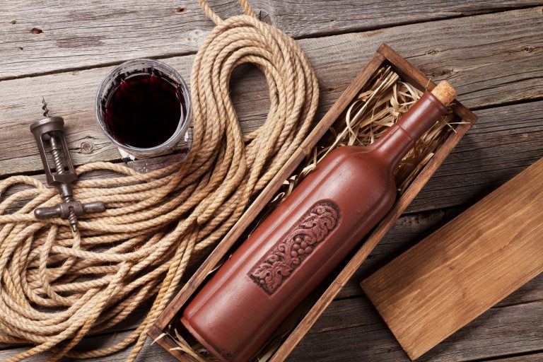 ticlă de vin roșu ceramică într-o cutie de lemn, alături de un pahar de vin bun